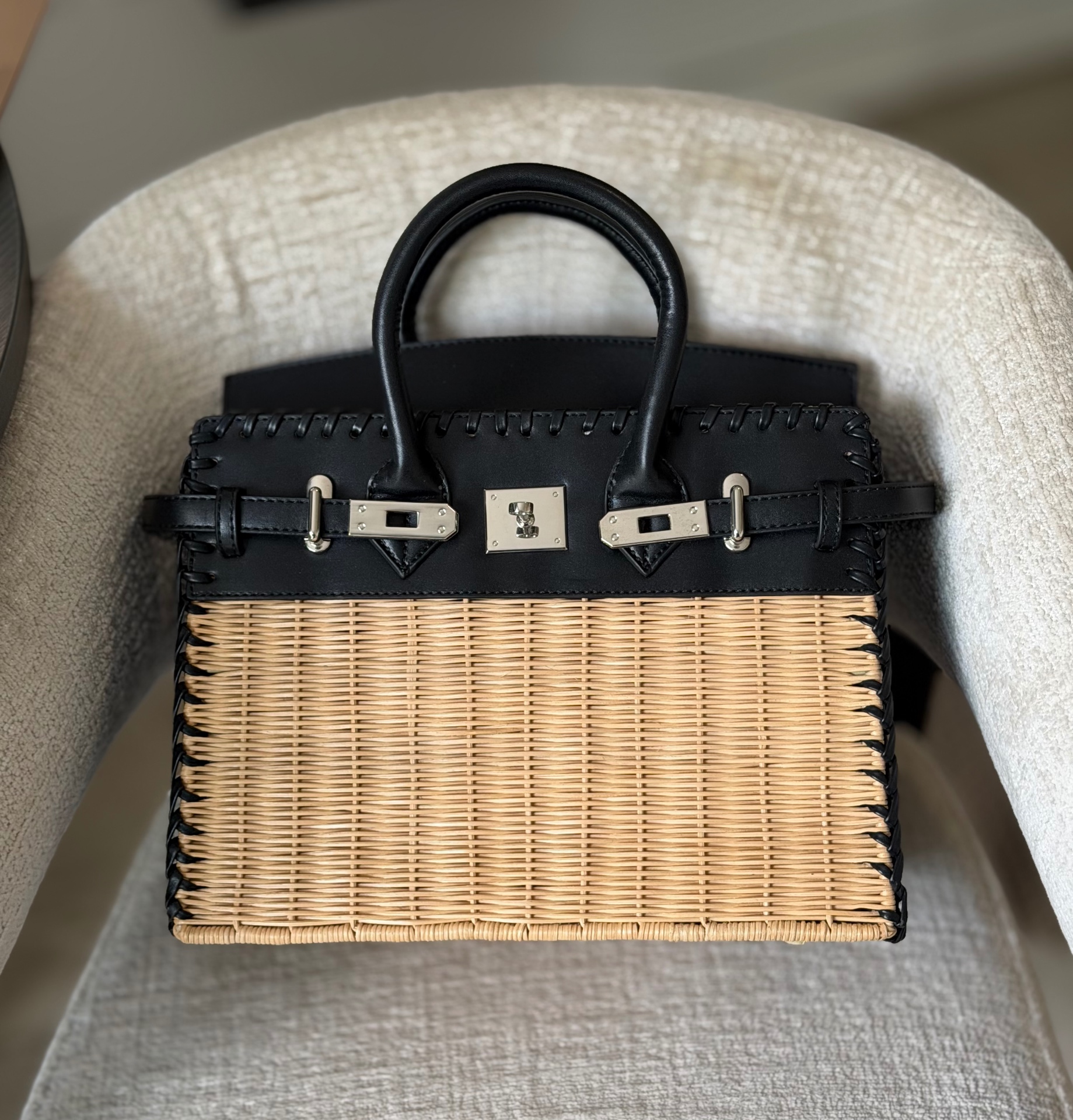BKn panier pique-nique d'Assinie — osier naturel et cuir noir, posé sur un fauteuil